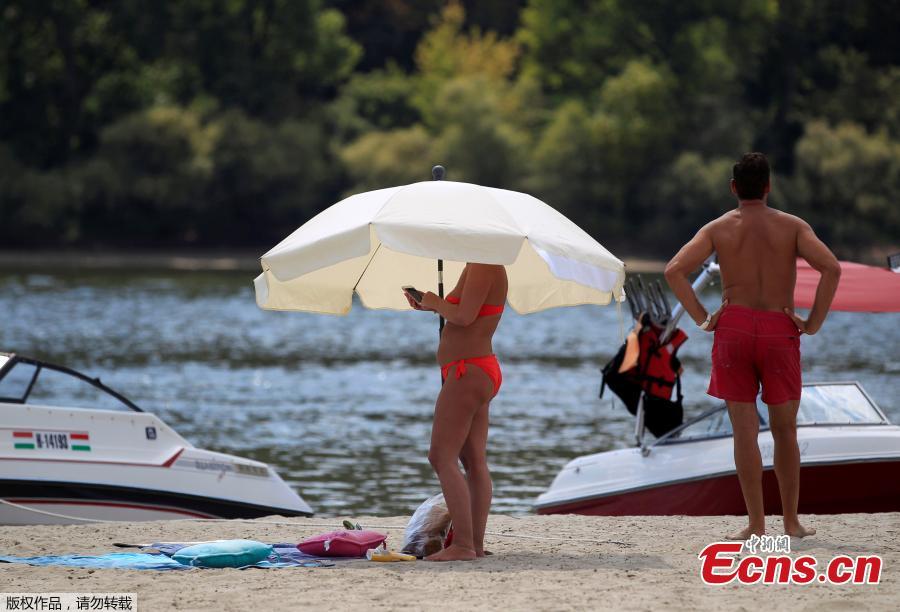 A woman covers herself under an umbrella on a gravel shoal in the middle of the Danube river during the period of low water level near Esztergom, Hungary, August 19, 2018. (Photo/Agencies)