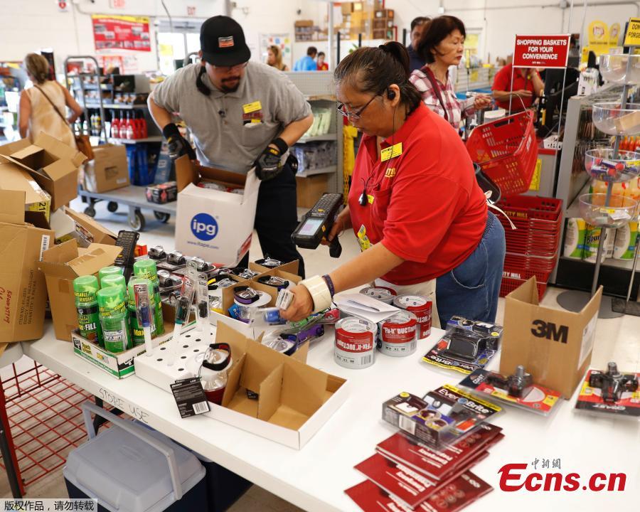 City Mill hardware store sales associates Frank Miller Gascon, left, Lisa Lavilla, fill a table up with duck tape, flashlights, and other hurricane supplies in Honolulu, Aug. 22, 2018. Gascon said he\'s been filling the table up every ten minutes as supplies are being swept up by shoppers who are preparing for the approaching Hurricane Lane. (Photo/Agencies)