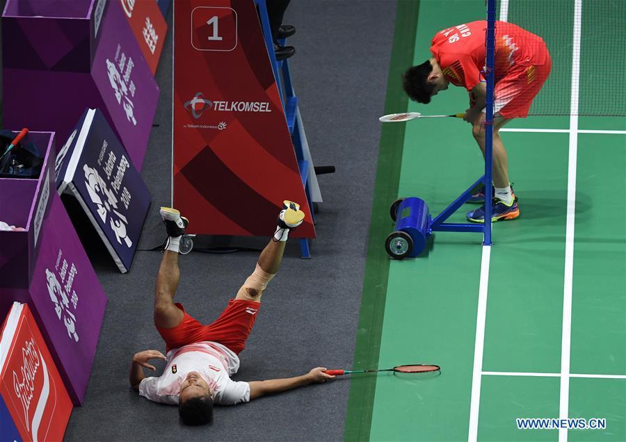 China\'s Shi Yuqi comes over as Indonesia\'s Anthony Sinisuka lies on the ground during the singles match of men\'s team final between China and Indonesia at the 18th Asian Games in Jakarta, Indonesia on Aug. 22, 2018. (Xinhua/Li Xiang)