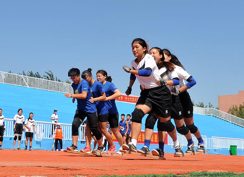 Competitors are race walking with team members’ feet fastened to a board at the 10th Provincial Traditional Ethnic Sports Games in Hebei Province, Aug. 21, 2018. (Photo by Yuan Liwei for chinadaily.com.cn)