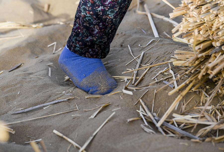 Because of the difficulty of walking in the desert, some of the women work only in socks. (Photo/Xinhua)
It was 7 pm, but the temperature was still above 50 C. To cool down, Zhang gulped down a bottle of water. There\'s nothing but sand as far as the eye can see. Eye problems are common among workers, and yet few quit. \