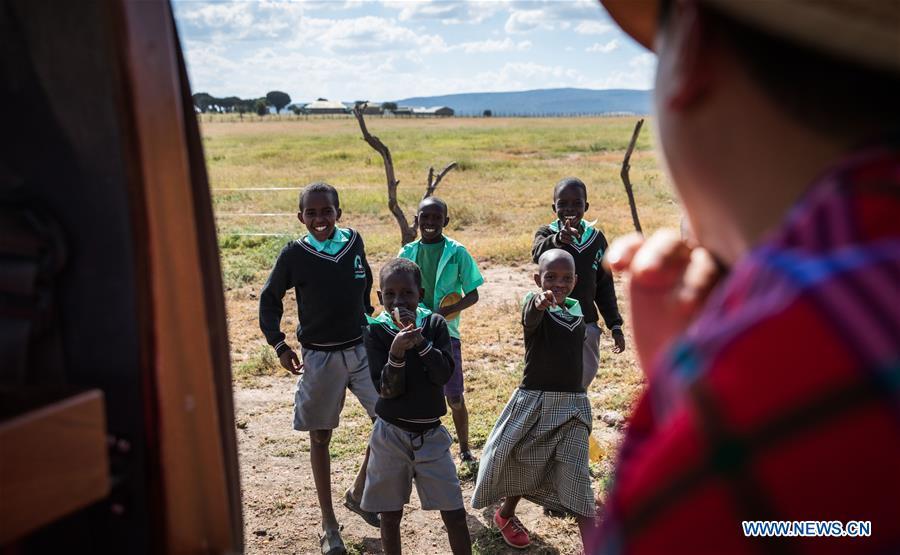 Children greet Chinese wildlife conservationist Zhuo Qiang (R) as he passes by in Maasai Mara, Kenya, July 6, 2018. The founder and Chairman of Mara Conservation Fund (MCF) Zhuo Qiang, a 45-year-old Chinese, has pioneered outstanding wildlife conservation projects in the world famous Maasai Mara ecosystem. Ol Kinyei is among the conservancies benefiting from his activities. Around it, he has built three lion proof boas preventing the wildlife conflict with the adjacent communities. He was officially adopted as a son of the Maasai\'s Ol Kinyei conservation group in 2015, owing to his unwavering friendship with the pastoralists. Zhuo\'s anti-poaching drives in the East African nation expresses the increasing collaboration between Kenyan and China in ending the killing of rhinos, elephants and lions. (Xinhua/Lyu Shuai)