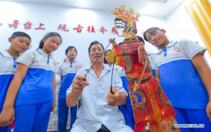 An artist explains knowledge of shadow puppet play for primary school students in Feixiang District of Handan, north China\'s Hebei Province, Aug. 25, 2017. (Xinhua/Wang Xiao)