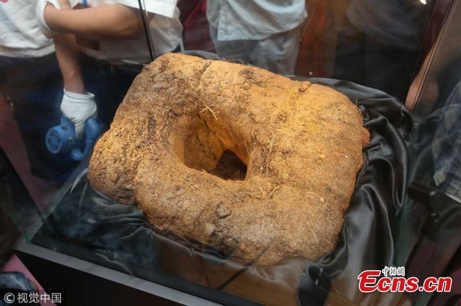 Visitors view a meteorite crater exhibited at a press conference held by Shanghai Planetarium in east China\'s Shanghai, Aug. 25, 2018. Shanghai Planetarium on Saturday announced plans to house meteorites recovered from a meteor fireball that happened over the sky in Jinghong City of southwest China\'s Yunnan Province in June. The planetarium, which is under construction, will be a branch of the Shanghai Science & Technology Museum. The museum staff have successfully recovered more than 500 pieces of meteorites, about 50 kg in total, said Lin Qing, deputy director in charge of the planetarium construction, at a press conference Saturday. (Photo/VCG)
