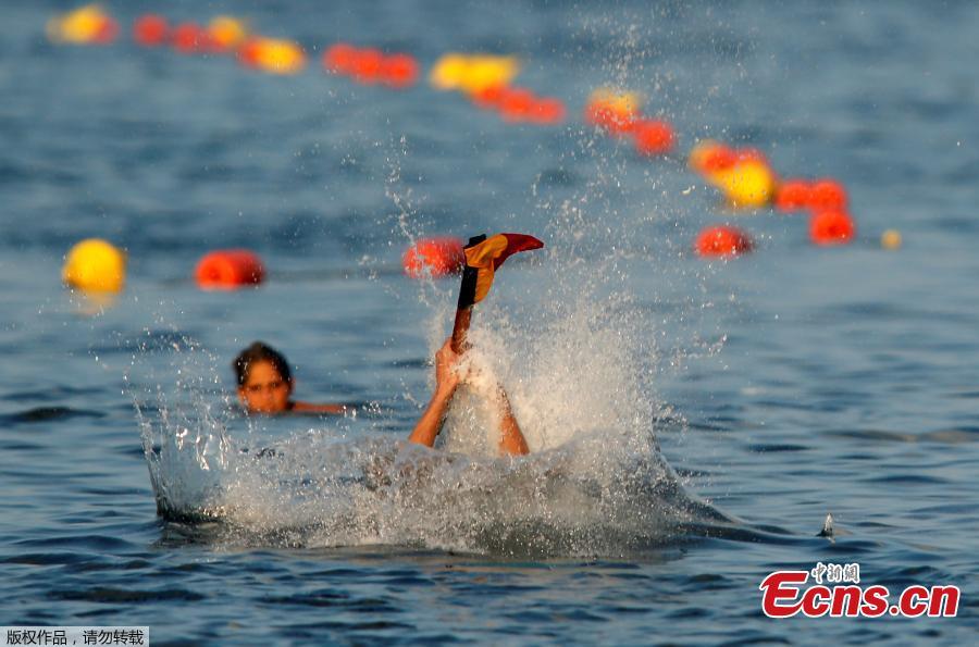 A competitor plunges into the sea while clutching the final flag after falling off the \