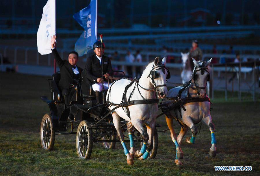 People ride a horse-dragging carriage during the opening ceremony of a horse-themed art week in Hohhot, capital of north China\'s Inner Mongolia Autonomous Region, Aug. 27, 2018. Kicked off here on Monday, the art week will include art performances, beer and food festival, and equestrian performances. (Xinhua/Peng Yuan)