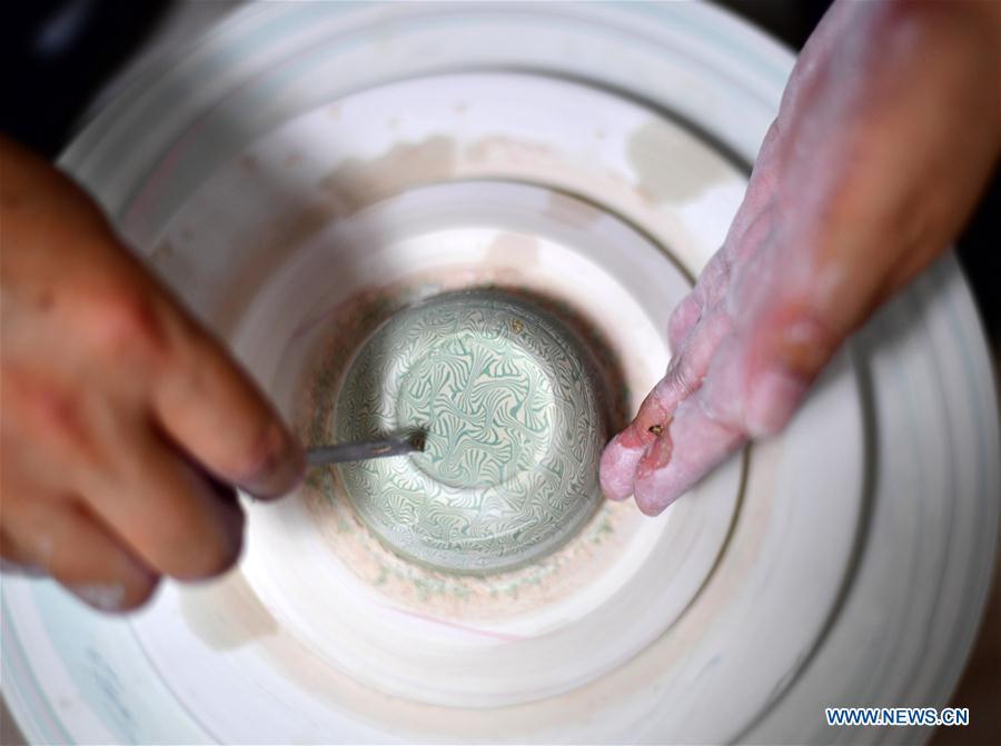 Chai Zhanzhu, the representative inheritor of Dangyangyu kiln Jiao Tai pottery firing, works on a greenware at Dangyangyu Village of Xiuwu County in Jiaozuo, central China\'s Henan Province, Aug, 27, 2018. The Dangyangyu kiln Jiao Tai pottery firing is a handicraft that was listed as a national intangible cultural heritage in 2014. The Jiao Tai pottery is made by blending clays of differing colours together, creating distinctive veined or mottled patterns. The handicraft is therefore recognized as \