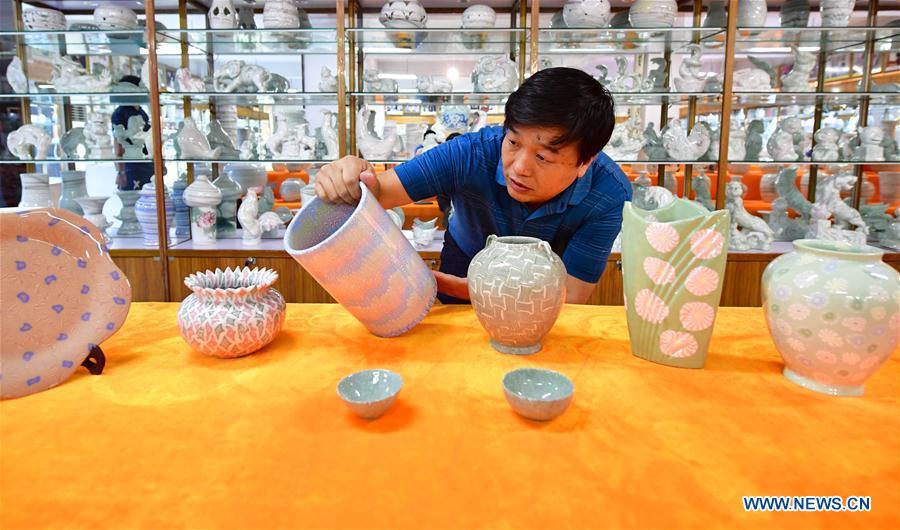Chai Zhanzhu, the representative inheritor of Dangyangyu kiln Jiao Tai pottery firing, observes a pottery at Dangyangyu Village of Xiuwu County in Jiaozuo, central China\'s Henan Province, Aug, 27, 2018. The Dangyangyu kiln Jiao Tai pottery firing is a handicraft that was listed as a national intangible cultural heritage in 2014. The Jiao Tai pottery is made by blending clays of differing colours together, creating distinctive veined or mottled patterns. The handicraft is therefore recognized as \