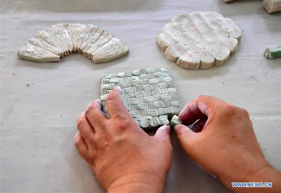 Chai Zhanzhu, the representative inheritor of Dangyangyu kiln Jiao Tai pottery firing, blends clays of differing colours together at Dangyangyu Village of Xiuwu County in Jiaozuo, central China\'s Henan Province, Aug, 27, 2018. The Dangyangyu kiln Jiao Tai pottery firing is a handicraft that was listed as a national intangible cultural heritage in 2014. The Jiao Tai pottery is made by blending clays of differing colours together, creating distinctive veined or mottled patterns. The handicraft is therefore recognized as \