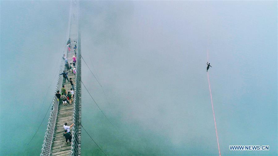 People watch a man walking on a webbing during a slacklining competition held in Shenxianju scenic spot in Xianju County, east China\'s Zhejiang Province, Aug. 25, 2018. (Xinhua/Zhu Cheng)