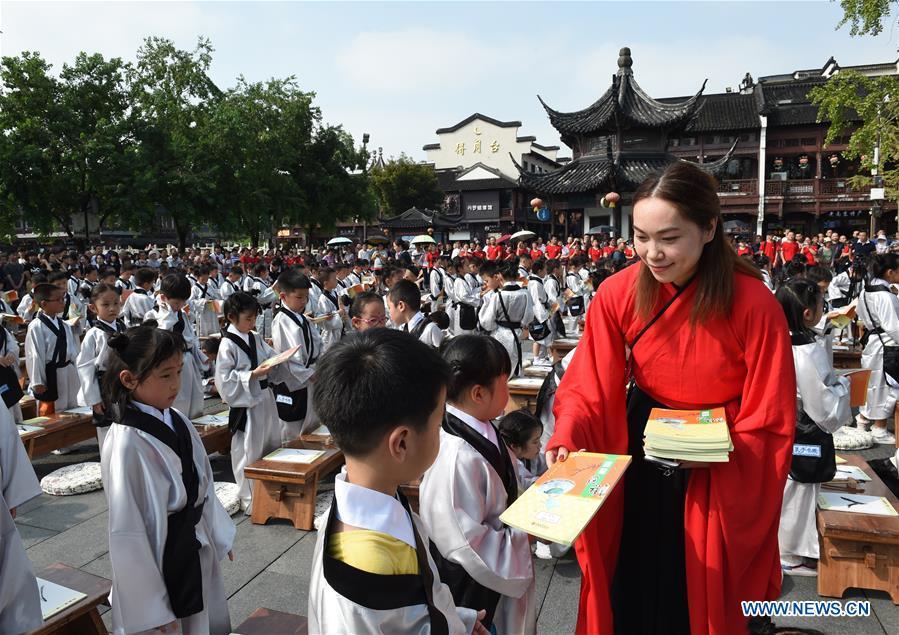 A teacher gives books to children during a first writing ceremony, a traditional education activity for first year students in China, in Nanjing, capital of east China\'s Jiangsu Province, Sept. 2, 2018. (Xinhua/Sun Can)