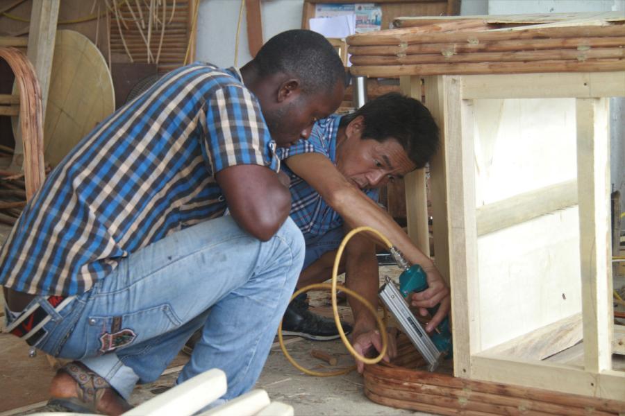A Chinese carpenter shows a Liberian colleague how to make rattan furniture at a training center in Monrovia, Liberia, on Aug. 20. (Photo/Xinhua)