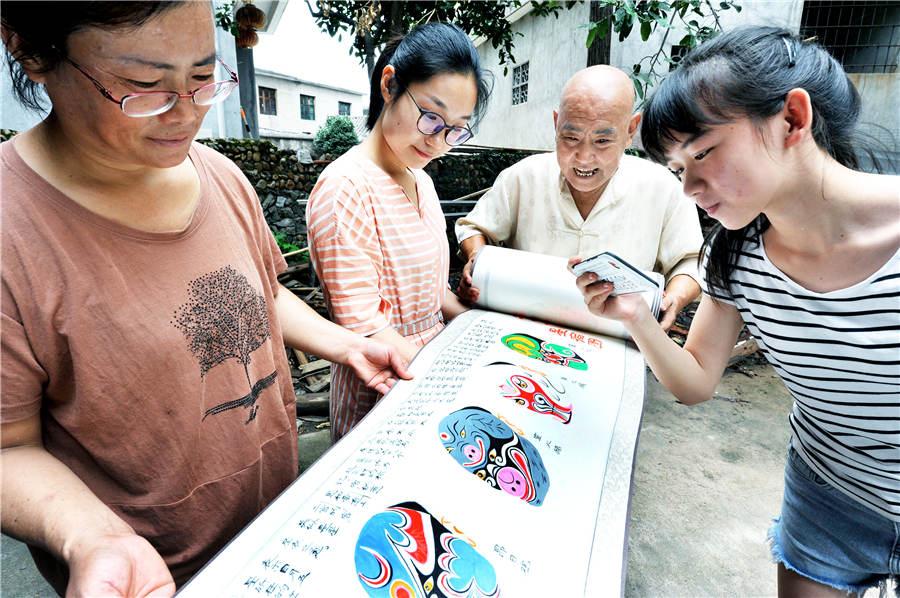 Zhao Xichun shows off his Peking Opera mask scroll in his workshop in Shaorao city, Jiangxi Province on Sept. 2, 2018. (Photo/Asianewsphoto)