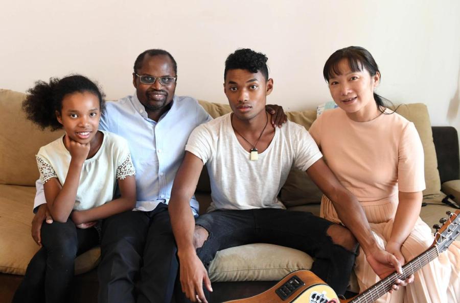 Traditional Chinese medicine practitioner Diarra Boubacar from Mali poses for photo with his wife and two children at home in Kunming, Yunnan Province, on Aug. 28. (Photo/Xinhua)