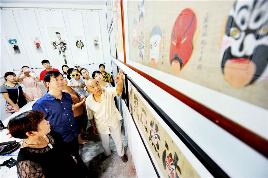 Zhao Xichun introduces his Peking Opera mask scroll in his workshop in Shaorao city, Jiangxi Province on Sept. 2, 2018. (Photo/Asianewsphoto)