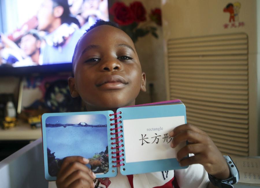 A boy, 6, from Malawi, shows his Chinese character cards at his home in Chengdu, Sichuan Province, in June. (Photo/China Daily)