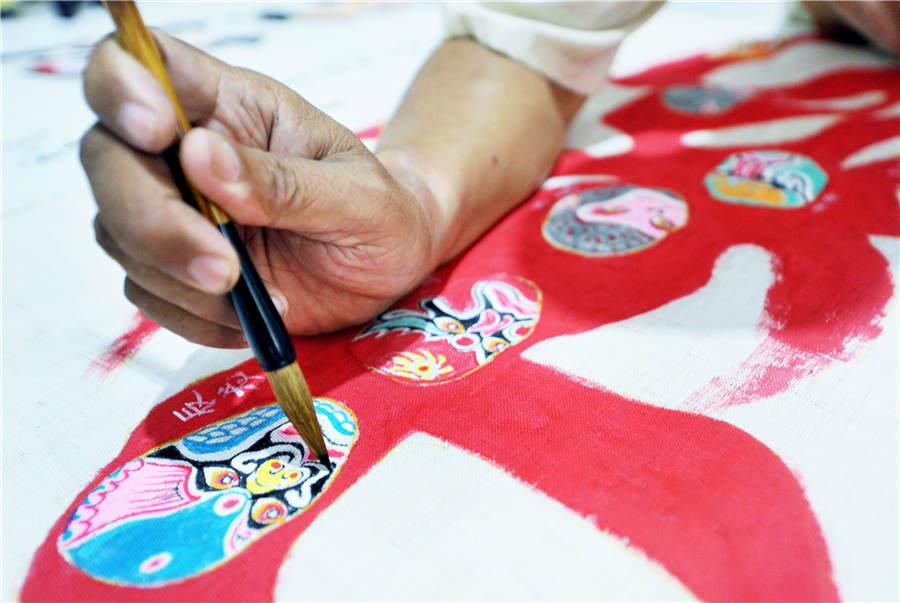 Zhao Xichun works on Peking Opera mask artwork in his workshop in Shaorao city, Jiangxi Province on Sept. 2, 2018. (Photo/Asianewsphoto)
Zhao Xichun, a retired man from Shaorao city in Jiangxi Province, has created a 56-meter-long scroll painted with 288 different Peking Opera masks. This makes it the longest Peking Opera mask scroll nationwide, as the previous record was only 30 meters long.
The scroll, based on figures from classic novels such as Investiture of the Gods, The Romance of the Three Kingdoms, Journey to the West and fairy tales such as \