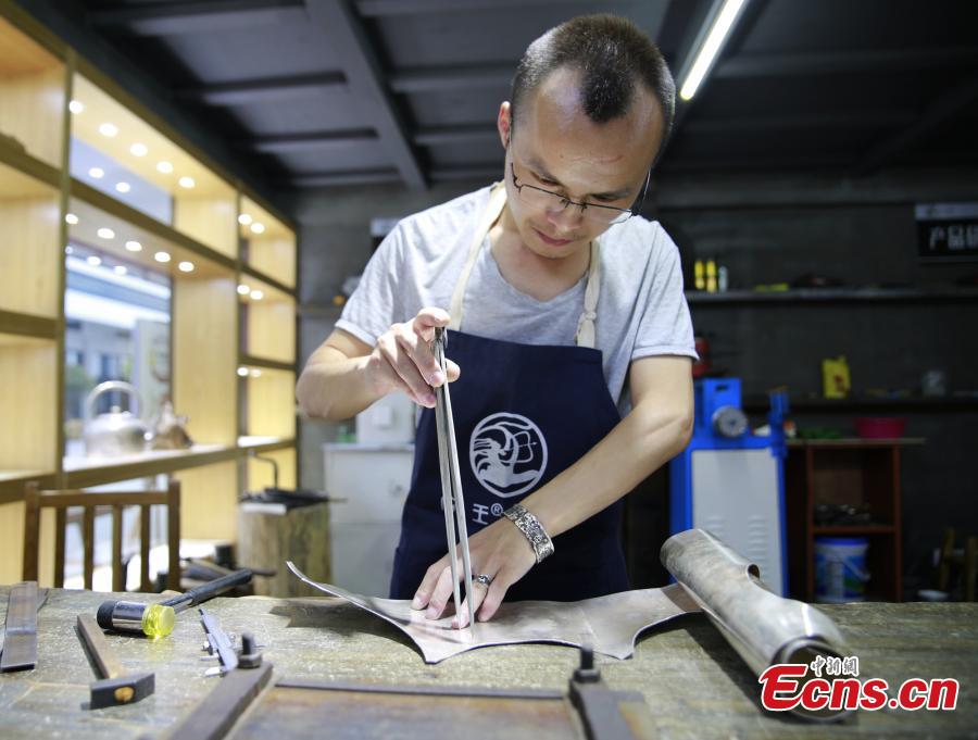 Yang Changgan makes a silver pot in his studio in Zhangjiajie City, Central China’s Hunan Province, Sept. 5, 2018. Yang, born in 1986 in Guizhou Province, was exposed to the craft of silverwork from an early age. After completing his bachelor’s degree at Nanchang Institute of Technology in 2010, he learned with Yang Guangbin, a master crafter of the silver ornaments of the Miao people. He then opened his own studio in Zhangjiajie in 2015, mainly developing silver pot products. Yang said it takes 10-15 days to make a silver pot as the process involves nearly 100 steps, including pounding, refining and wielding. Yang said his creations sell well in nearly 20 countries and regions. (Photo: China News Service/Wu Yongbing)
