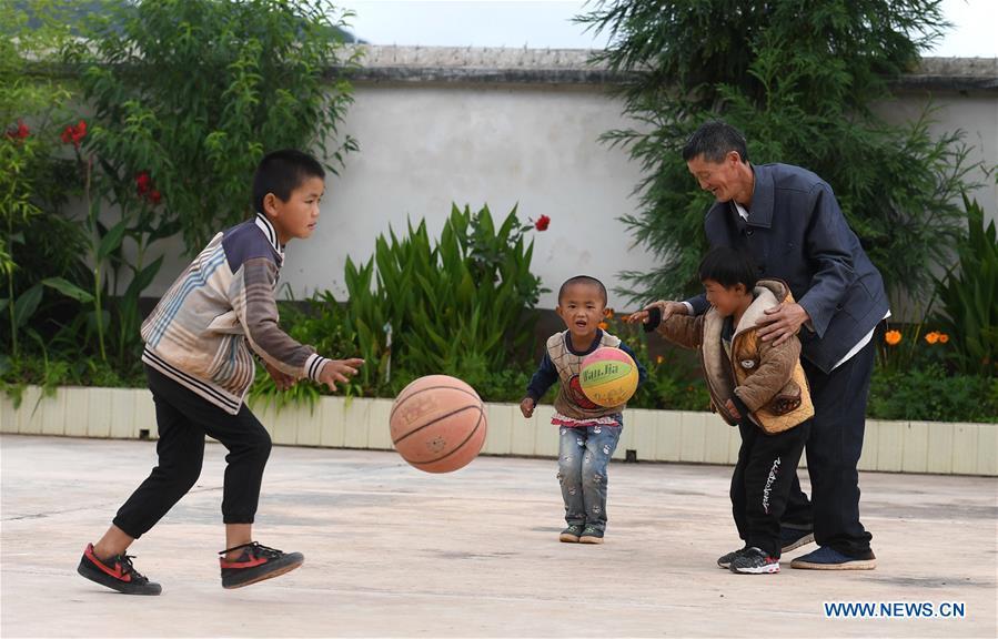 Wang Zhengxiang plays with students at Ayiyang Primary School in Sanmeng Village of Luquan Yi and Miao Autonomous County, southwest China\'s Yunnan Province, Sept. 6, 2018. One teacher, eight students, none was and will be given up thanks to rural teacher Wang Zhengxiang. Wang Zhengxiang of Miao ethnic group, 56, is the only teacher and has been teaching at the remote village primary school of Ayiyang for 38 years. Ayiyang Primary School, lying at an altitude of 2,600 meters above sea level and surrounded by mountains, is not within easy reach of outside world. There are just eight students at the school. Yet Wang takes care of his students with love, consideration and strong sense of responsibility. He buys shoes and daily goods for poverty-stricken students with his own money, and he has tried every means to keep those who wanted to drop out due to economic insufficiency. \