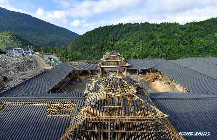 A worker lays tiles on the rooftop in the construction site of a Dong ethnic group relocation compound in Yejiaoyuan Village of Xuan\'en County, central China\'s Hubei Province, Sept. 8, 2018. The residence compound, a relocation project aimed at aiding the 40 local families that live under the poverty line, is designed to boost the local tourism as the buildings feature the Dong ethnic group originality that may attract tourists for a culture experience. (Xinhua/Song Wen)