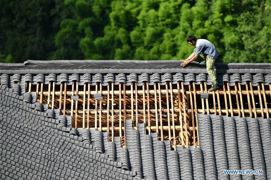 A worker lays tiles on the rooftop in the construction site of a Dong ethnic group relocation compound in Yejiaoyuan Village of Xuan\'en County, central China\'s Hubei Province, Sept. 8, 2018. The residence compound, a relocation project aimed at aiding the 40 local families that live under the poverty line, is designed to boost the local tourism as the buildings feature the Dong ethnic group originality that may attract tourists for a culture experience. (Xinhua/Song Wen)