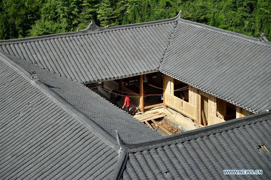 A worker walks in the construction site of a Dong ethnic group relocation compound in Yejiaoyuan Village of Xuan\'en County, central China\'s Hubei Province, Sept. 8, 2018. The residence compound, a relocation project aimed at aiding the 40 local families that live under the poverty line, is designed to boost the local tourism as the buildings feature the Dong ethnic group originality that may attract tourists for a culture experience. (Xinhua/Song Wen)