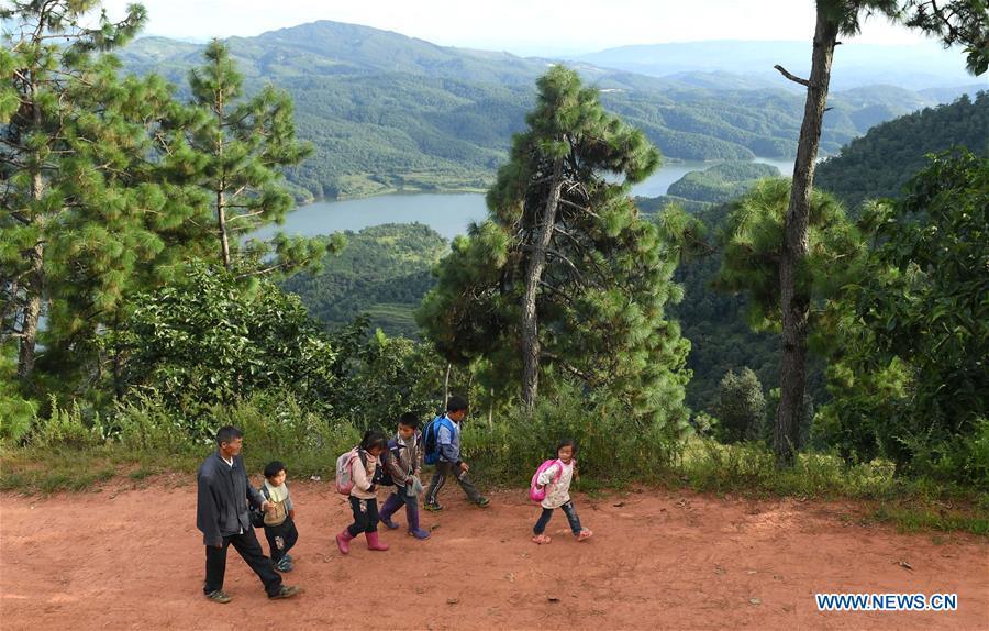 Wang Zhengxiang sends students back home after school in Sanmeng Village of Luquan Yi and Miao Autonomous County, southwest China\'s Yunnan Province, Sept. 5, 2018. One teacher, eight students, none was and will be given up thanks to rural teacher Wang Zhengxiang. Wang Zhengxiang of Miao ethnic group, 56, is the only teacher and has been teaching at the remote village primary school of Ayiyang for 38 years. Ayiyang Primary School, lying at an altitude of 2,600 meters above sea level and surrounded by mountains, is not within easy reach of outside world. There are just eight students at the school. Yet Wang takes care of his students with love, consideration and strong sense of responsibility. He buys shoes and daily goods for poverty-stricken students with his own money, and he has tried every means to keep those who wanted to drop out due to economic insufficiency. \