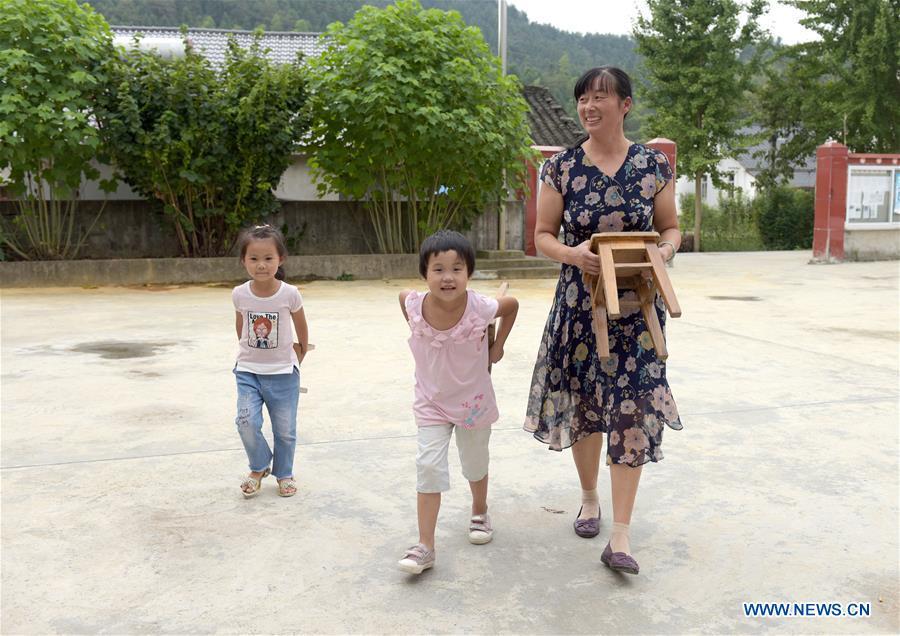 Jiang Xiulan prepares a game with students between classes in Qingxi Central Primary School in Chaerlong village, Wushi town, Huangshan City of east China\'s Anhui Province, Sept. 7, 2018. Since 1983 when she began her career as a teacher, Jiang has been working in the \