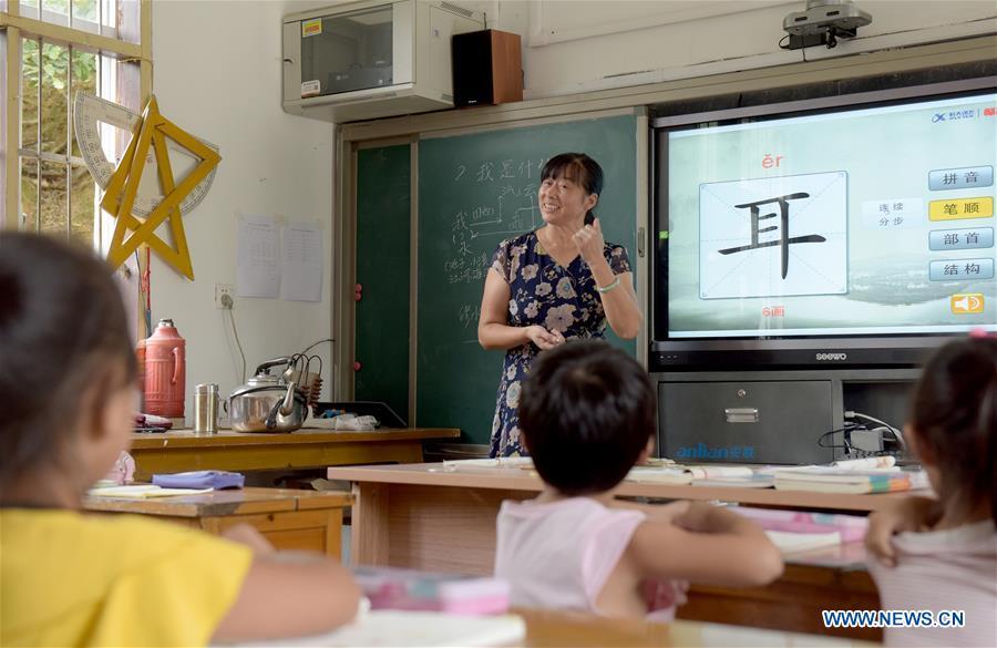 Jiang Xiulan, 53, explains the meaning of a Chinese character as she teaches in a class of Qingxi Central Primary School in Chaerlong village, Wushi town, Huangshan City of east China\'s Anhui Province, Sept. 7, 2018. Since 1983 when she began her career as a teacher, Jiang has been working in the \