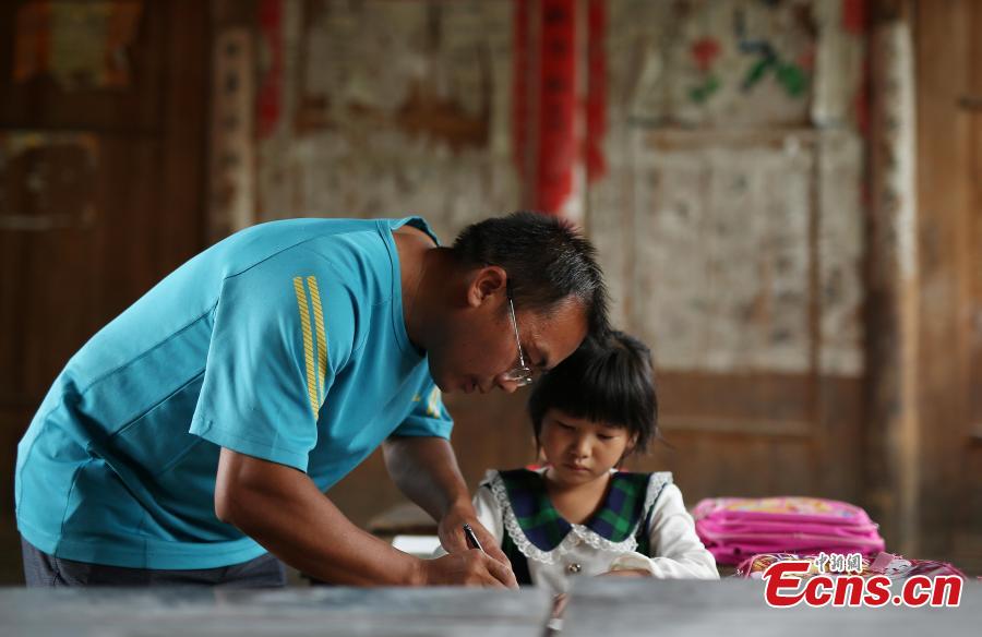 Teacher Yang Changjun instructs Wang Fangying, a first grader, in writing at a school in Danggan Village, Paitiao Town, Guizhou Province, Sept. 7, 2018. Yang, 40, is the only teacher in the school that has one first grader and seven pre-school children from nearby villages. If not for the school, children would have to travel to a town more than 20 kilometers away to study. (Photo: China News Service/Huang Xiaohai)