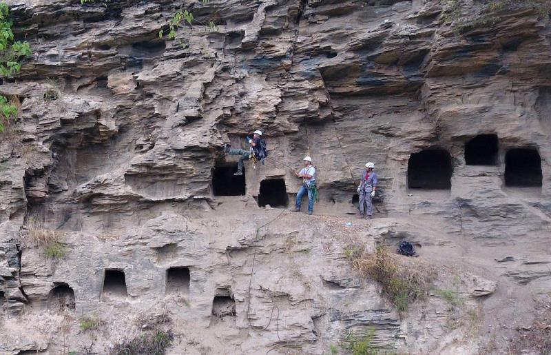 An archaeological worker is suspended in the air while colleagues watch as they excavate a site reached by rock climbing in Yangpitan, Yunxi county, Central China\'s Hubei Province. (Photo by Zhang Jianbo for chinadaily.com.cn)