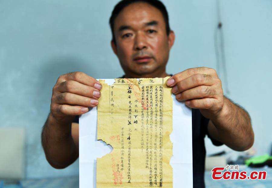 Wang Zhiliang shows a stock certificate issued in 1939 in Xiatan Village, Pingshan County, North China’s Hebei Province, Sept. 11, 2018. Wang said his grandfather, Wang Jinyun, purchased the stock to support the war against Japanese aggression in 1939, issued by the local government of the time. (Photo: China News Service/Zhai Yujia)