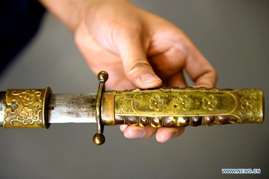 Yan Min displays a repaired ancient weapon in Shijiazhuang, north China\'s Hebei Province, Sept. 11, 2018. Yan Min, dedicated to ancient weapon restoration for more than 30 years, has hitherto repaired over 500 pieces of ancient weapons with his son Yan Peng. Influenced by his father, Yan Peng quit his job and embarked on restoring ancient weapons in the year of 2015. The sophisticated craftsmanship of ancient weapon restoration embodies working procedures of polishing, burnishing, grinding etc. \