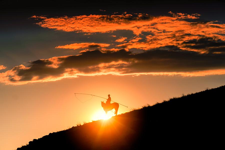 Autumn brings beautiful sunsets over open grasslands at Xilin Gol league in the Inner Mongolia autonomous region. Bathing in the sunset glow, working horses and herdsmen create a picturesque setting. (Photo/China Daily)