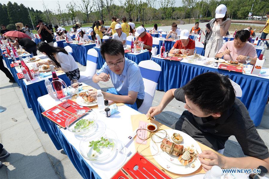 Tourists enjoy dishes made from Chinese mitten crabs during a tourist festival held ashore the Yangcheng Lake in Xiangcheng District of Suzhou, east China\'s Jiangsu Province, Sept. 19, 2018. The Chinese mitten crabs inhabiting Suzhou\'s Yangcheng Lake are a popular cooking ingredient for many food lovers. In the annual event which kicked off here on Wednesday, tourists will be able to have a taste of this year\'s first Chinese mitten crabs ready to serve the table, while the official netting of Yangcheng Lake crabs will begin on Sept. 21. (Xinhua/Hao Qunying)