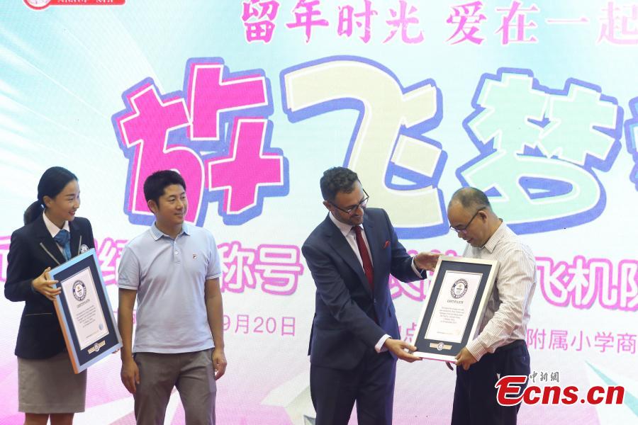 Marco Frigatti (second from right), Global Records senior vice-president of Greater China at Guinness World Records, grants certificates to the organizers of the paper aircrafts activity, in Beijing, Sept 20, 2018. Children from 22 provinces and cities made more than 60,000 paper planes, of which 14,285 were selected to create a line measuring 3,029.02 meters in length. It\'s the world\'s longest line of paper aircrafts and set a new Guinness World Record. The project was initiated by the China Children and Teenagers\' Fund and the Sister Ma Food Company in May. (Photo: China News Service/Sheng Jiapeng)