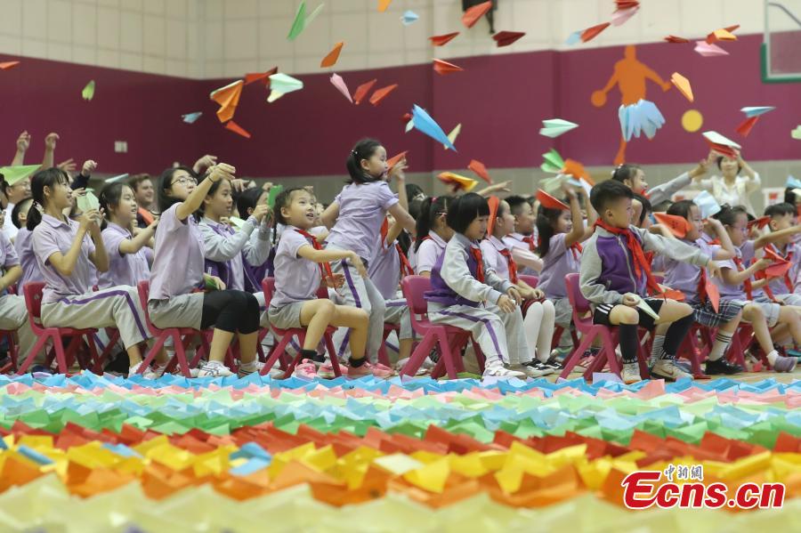 Primary school students fly paper aircrafts during an attempt to set a world record in Beijing, Sept. 20, 2018. Children from 22 provinces and cities made more than 60,000 paper planes, of which 14,285 were selected to create a line measuring 3,029.02 meters in length. It\'s the world\'s longest line of paper aircrafts and set a new Guinness World Record. The project was initiated by the China Children and Teenagers\' Fund and the Sister Ma Food Company in May. (Photo: China News Service/Sheng Jiapeng)