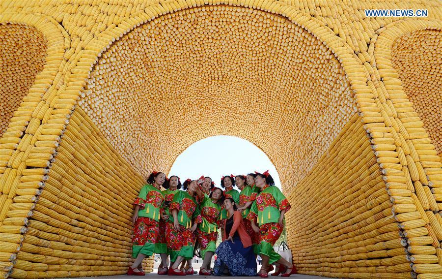 People pose for photos under an archway made of various harvested crops in a tourist spot in Handan, north China\'s Hebei Province, Sept. 22, 2018. China will mark its first Farmers\' Harvest Festival on Sept. 23 this year. From 2018 on, the festival, to be celebrated on the Autumnal Equinox each year, is set to be observed annually to greet the harvest season and honour the agricultural workers. (Xinhua/Hao Qunying)