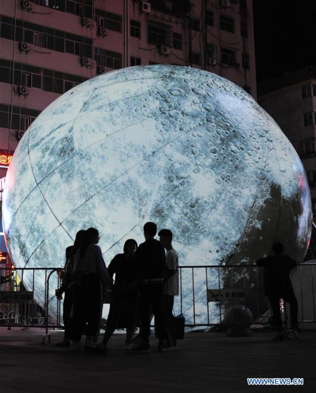 Pedestrians look at a moon installation set up to mark the upcoming Mid-Autumn Festival in front of a department store in Shiyan, central China\'s Hubei Province, Sept. 23, 2018. (Xinhua/Zhang Xinjun)