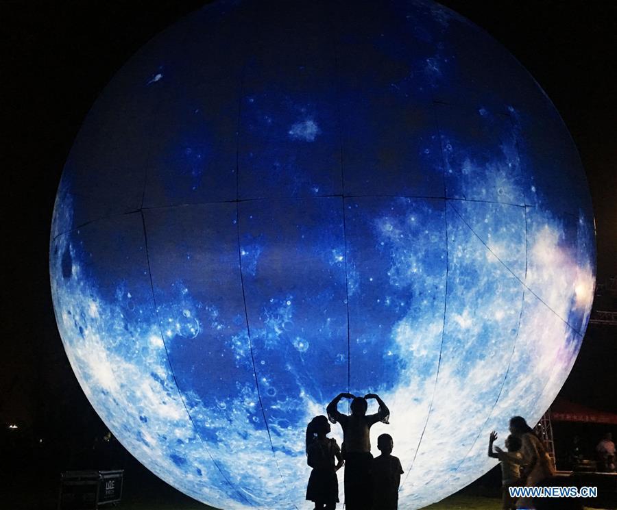 Pedestrians pose for photos with a moon installation set up to mark the upcoming Mid-Autumn Festival in Bozhou, east China\'s Anhui Province, Sept. 23, 2018. (Xinhua/Ni Shubin)