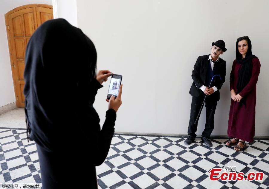 A woman takes a picture of Afghanistan\'s Charlie Chaplin, Karim Asir, 25, after his performance in Kabul, Afghanistan, Aug. 29, 2018.  Karim Asir says he has witnessed suicide attacks, explosions and threats from hardline Islamic militant groups, but is determined to waddle and bumble to fulfill the primary goal of his life. (Photo/Agencies)
