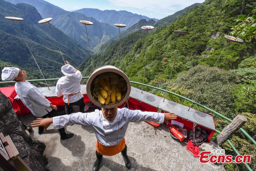 Chefs show stunt skills with kitchenware at a restaurant built on a cliff at Longquan Mountain in Zhejiang Province, Sept. 27, 2018. The restaurant 1,600 meters above sea level allows customers to dine on suspended plank roads while enjoying great views of the mountain. Longquan is the highest peak in the Yangtze River Delta. (Photo: China News Service/Yang Yong)