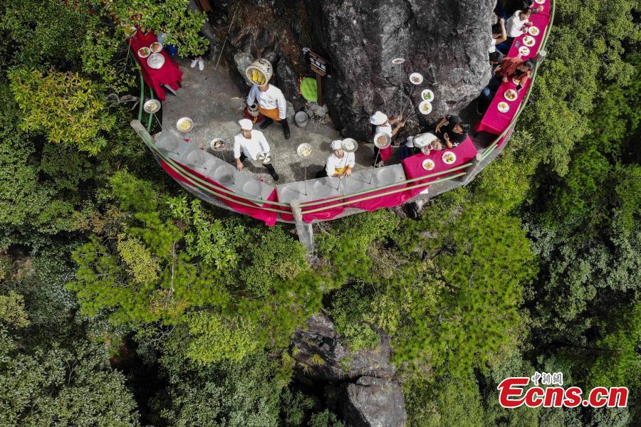 Chefs show stunt skills with kitchenware at a restaurant built on a cliff at Longquan Mountain in Zhejiang Province, Sept. 27, 2018. The restaurant 1,600 meters above sea level allows customers to dine on suspended plank roads while enjoying great views of the mountain. Longquan is the highest peak in the Yangtze River Delta. (Photo: China News Service/Yang Yong)