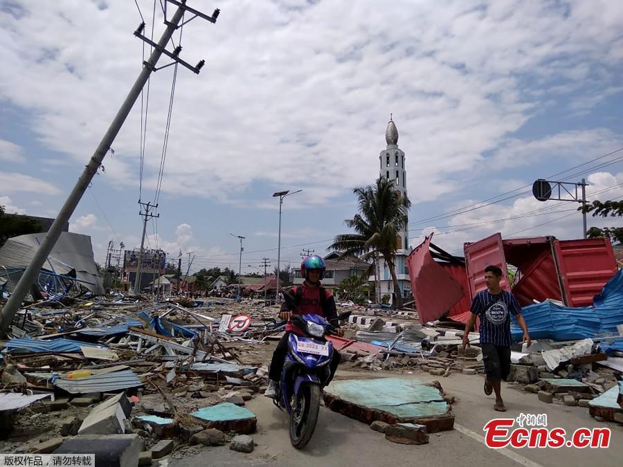Residents make their way along a street full of debris after an earthquake and tsunami hit Palu, on Sulawesi island on September 29, 2018. Rescuers scrambled to reach tsunami-hit central Indonesia and assess the damage after a strong quake brought down several buildings and sent locals fleeing their homes for higher ground. (Photo/Agencies)