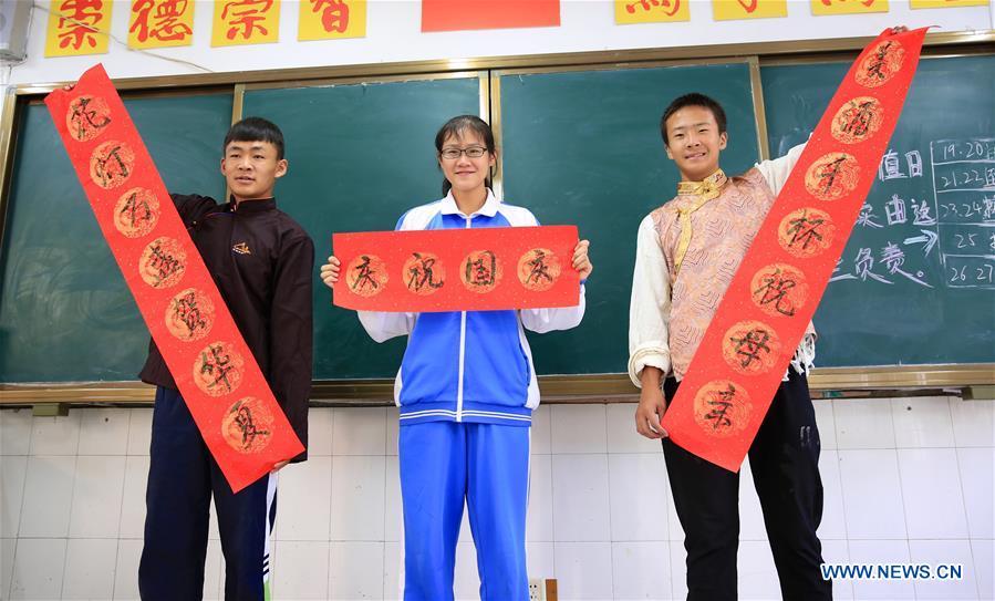 A student of the Han ethnic group (C) displays works of calligraphy with peers of the Tibetan ethnic group in Nanchang, capital of east China\'s Jiangxi Province, Sept. 30, 2018. Some 20 students of the Tibetan ethnic group from the No. 17 Middle School celebrated China\'s National Day with local residents and students. China\'s National Day falls on Oct. 1.(Xinhua/Hu Chenhuan)