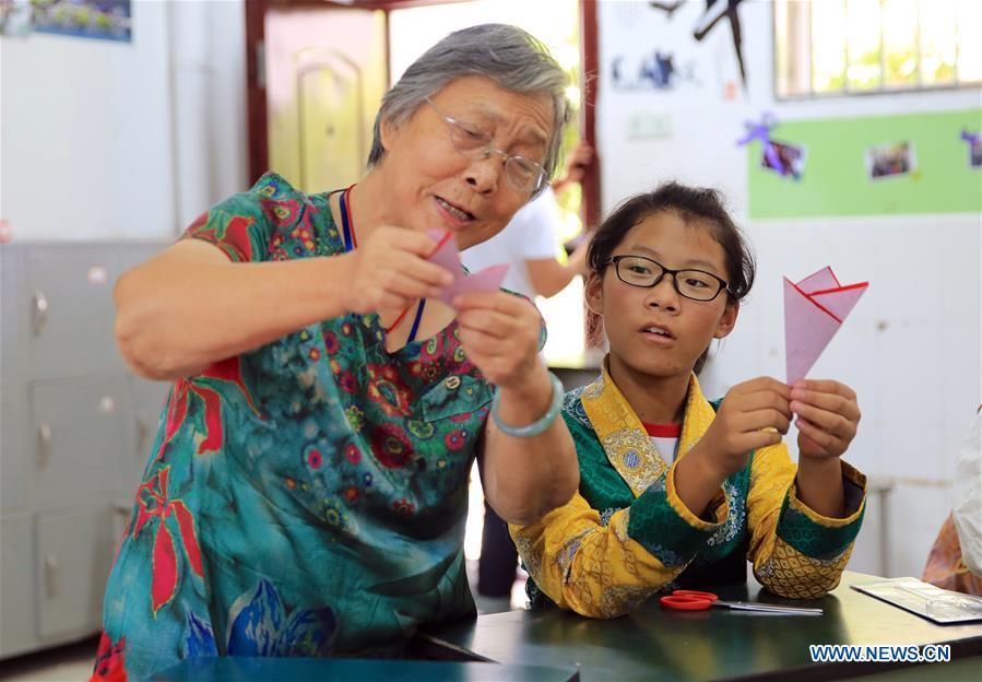 A resident (L) instructs a student of Tibetan ethnic group on paper cutting in Nanchang, capital of east China\'s Jiangxi Province, Sept. 30, 2018. Some 20 students of the Tibetan ethnic group from the No. 17 Middle School celebrated China\'s National Day with local residents and students. China\'s National Day falls on Oct. 1. (Xinhua/Hu Chenhuan)
