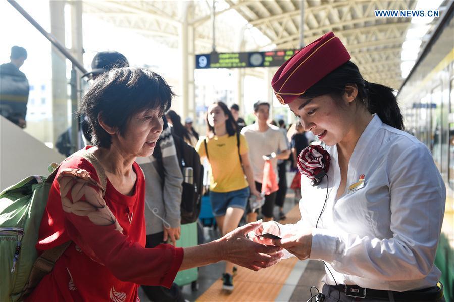 A passenger (L) consults a staff member before boarding at a railway station in Nanchang, capital of east China\'s Jiangxi Province, Oct. 1, 2018. The country witnesses a travel rush as people embark on trips for seven-day National Day holiday, which lasts from Oct. 1 to 7. (Xinhua/Bao Gansheng)
