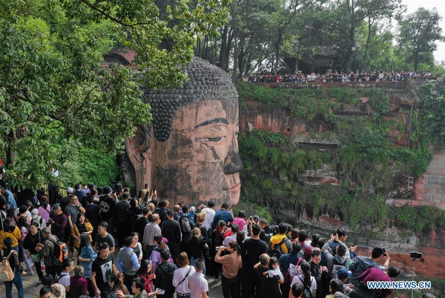 People view the statue of the Leshan Giant Buddha in Leshan City, southwest China\'s Sichuan Province, Oct. 4, 2018. The Leshan Buddha scenic area received about 43,800 visitors on the fourth day of China\'s National Day holiday. (Xinhua/Jiang Hongjing)