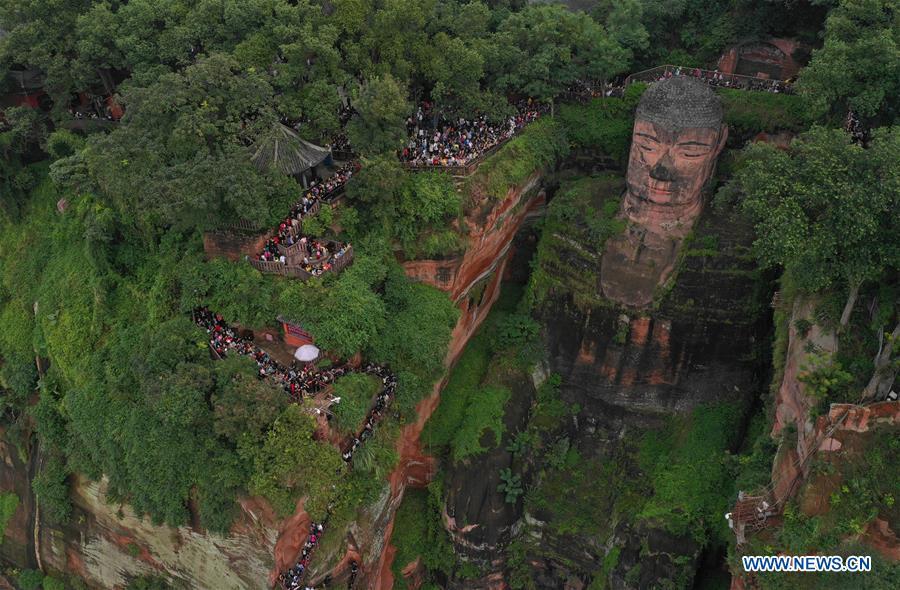 People view the statue of the Leshan Giant Buddha in Leshan City, southwest China\'s Sichuan Province, Oct. 4, 2018. The Leshan Buddha scenic area received about 43,800 visitors on the fourth day of China\'s National Day holiday. (Xinhua/Jiang Hongjing)