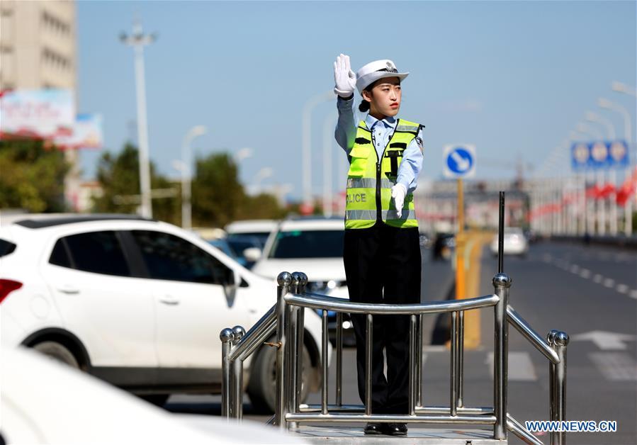 A police officer directs the traffic in Wu\'an City, north China\'s Hebei Province, Oct. 4, 2018. People from various sectors stick to their posts during the National Day holiday. (Xinhua/Wang Xiao)